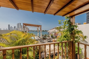 Eine Dachterrasse mit einer Holz-Pergola, Sitzgelegenheiten im Freien und Blick auf die Stadtlandschaft.