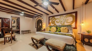 Un dormitorio con cama, techo de madera, zona de comedor con sillas y una pared con un panel decorativo.