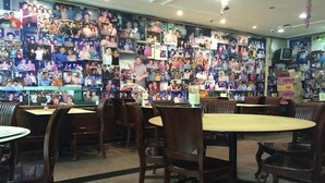 Ein Restaurant mit mehreren Tischen und Stühlen, einer Wand voller Fotos und einem Fernseher an der Wand.