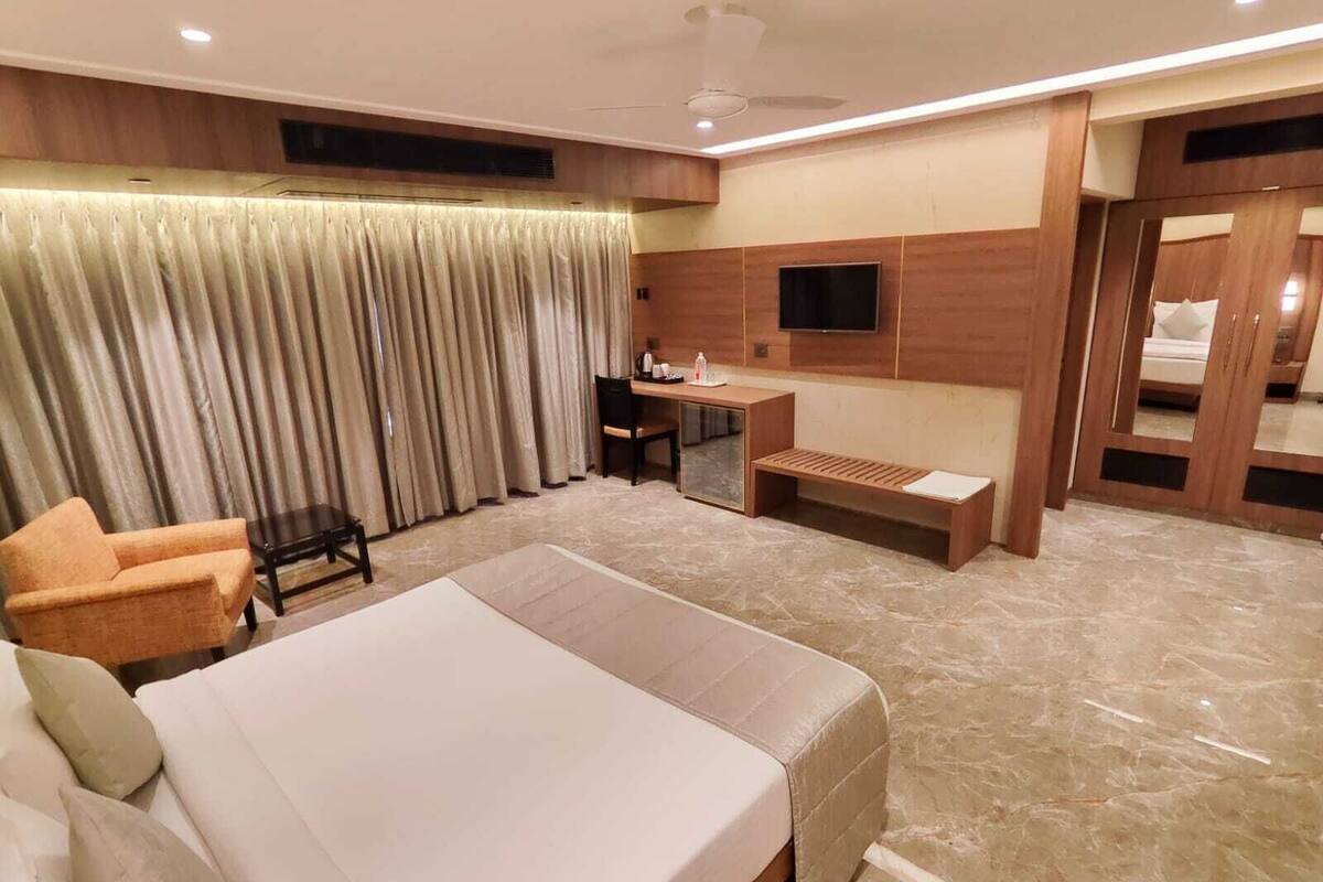 A hotel room with a large bed, a desk, a chair, and a sofa.