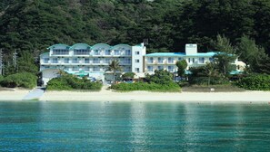 A beachfront hotel with multiple balconies, a swimming pool, and a beach access ramp. - Tokashiku Marine Village (OKINAWA)