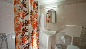 A bathroom with a shower curtain, sink, mirror, toilet, and tiled walls.