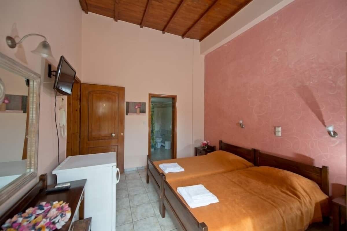 Een slaapkamer met een bed, een bureau met spiegel, een televisie en een garderobe.