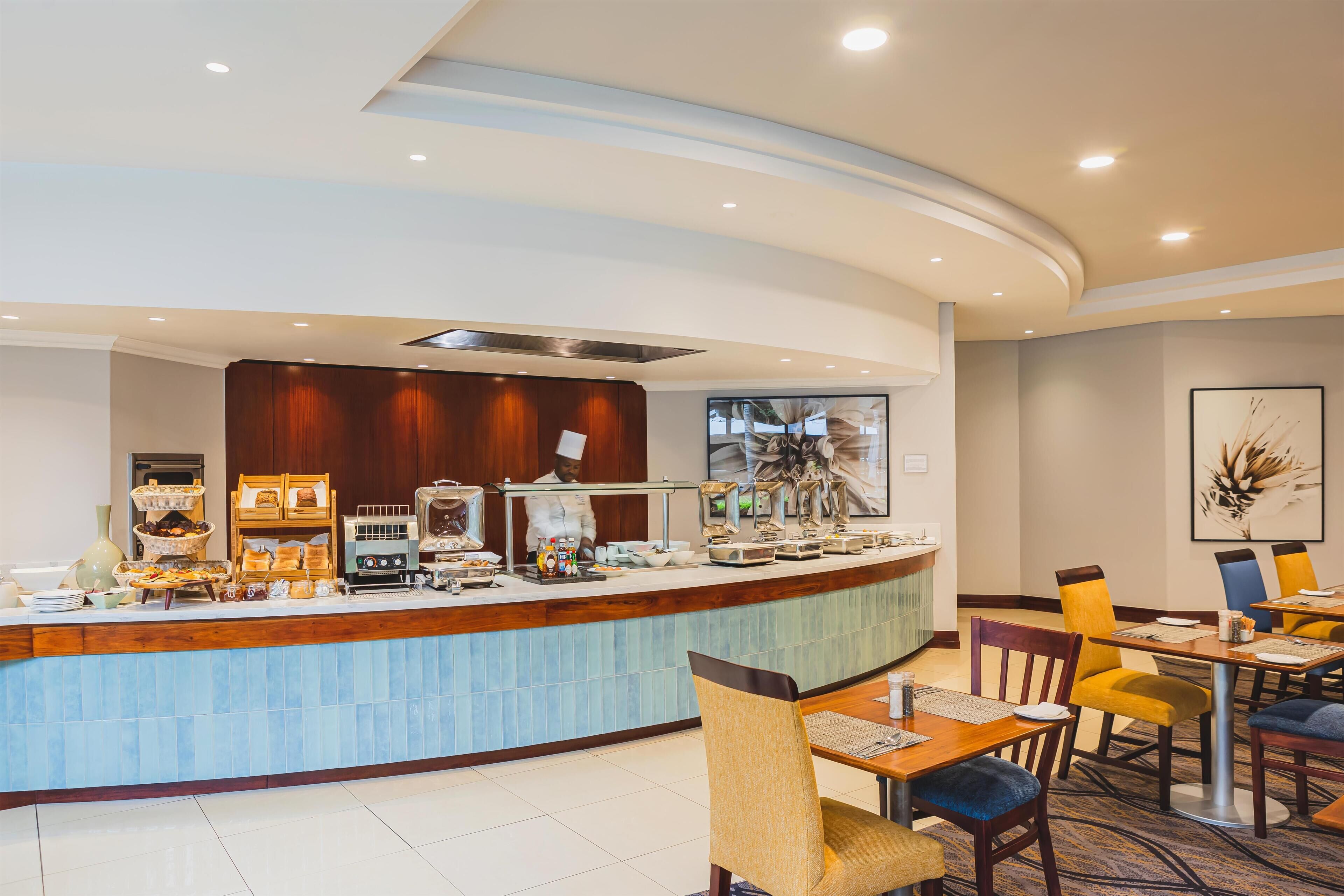 Un moderno hall de hotel con un mostrador de recepción curvo, zona de estar y un ventanal grande.