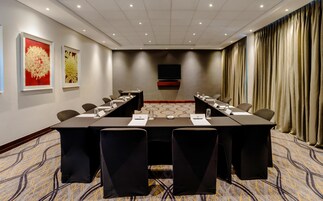 A conference room with a long table, chairs, a flat-screen TV, and artwork on the walls.