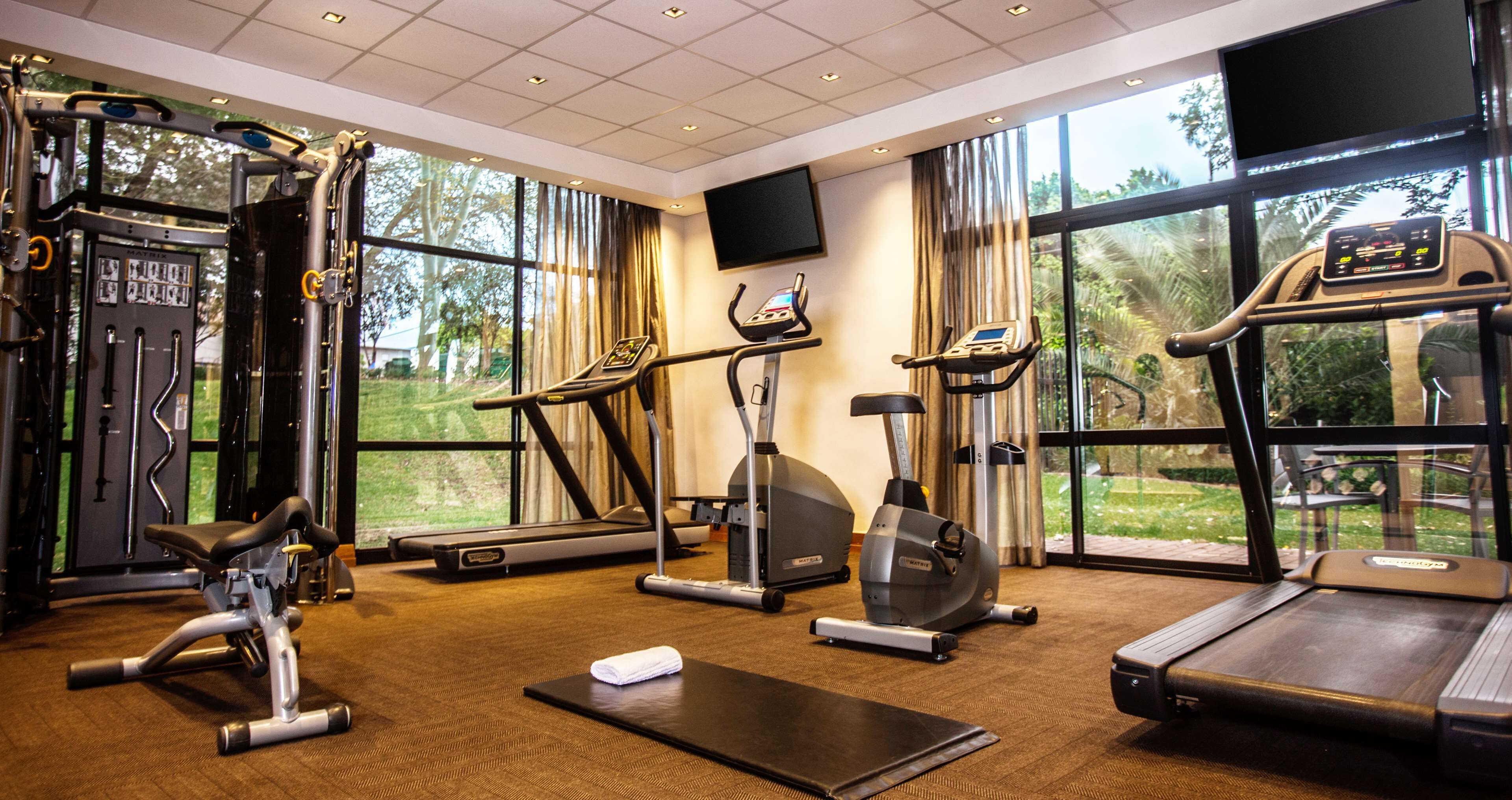 Ein Fitnessstudio mit unterschiedlichen Trainingsgeräten, großen Fenstern und einem Flachbildfernseher.