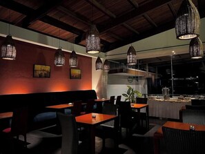 A restaurant with wooden tables and chairs, hanging wicker lamps, and a city view. - Puri Setiabudhi Residence (Bandung)