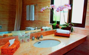 A bathroom with a marble sink, a mirror, a towel rack, a potted orchid, and a tissue box. - Puri Setiabudhi Residence (Bandung)
