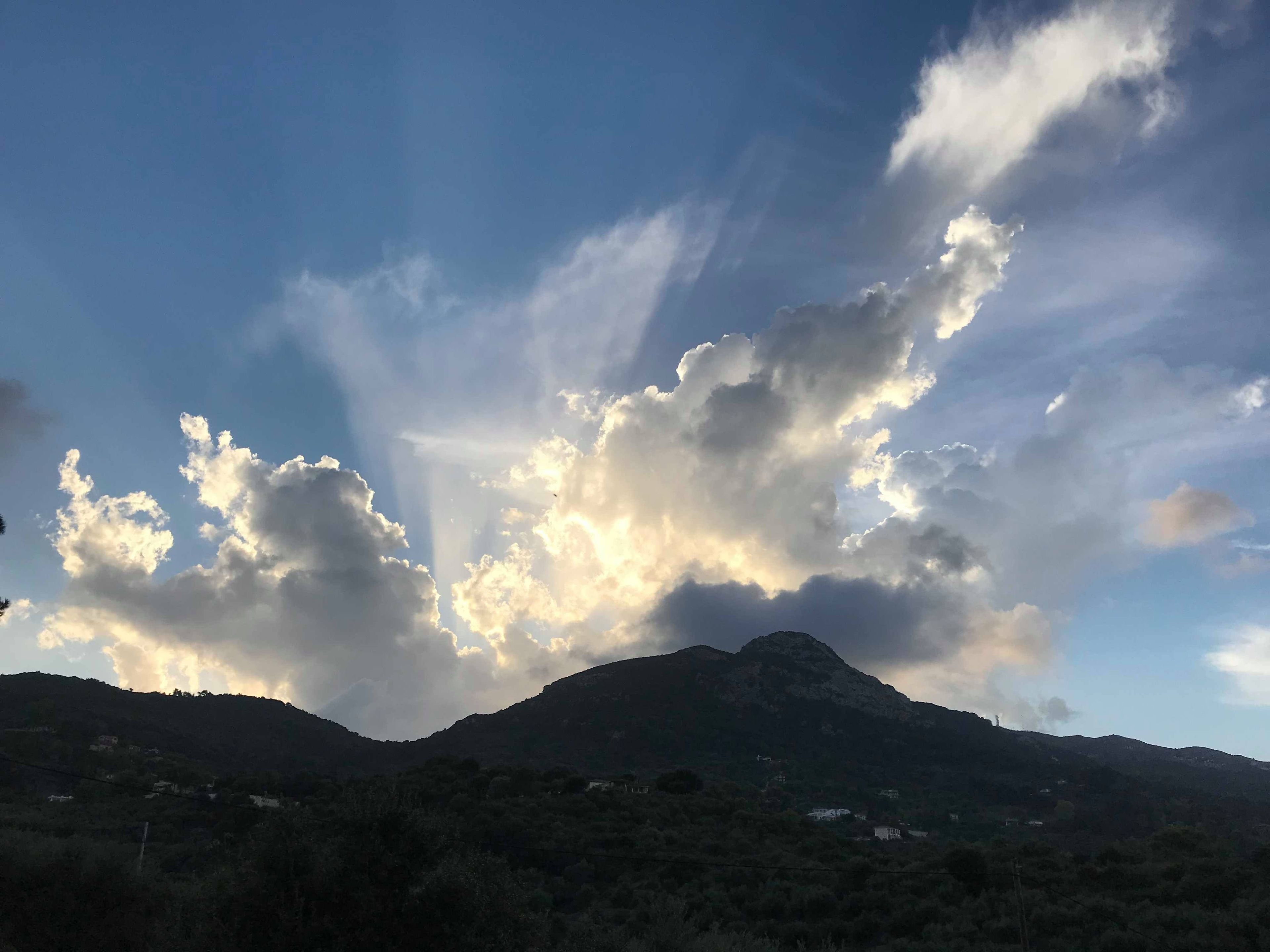 A mountain landscape with a clear sky and scattered clouds.
