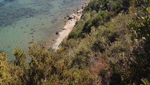 Une vue sur la côte, avec une plage, une eau cristalline et un bâtiment situé sur une colline.