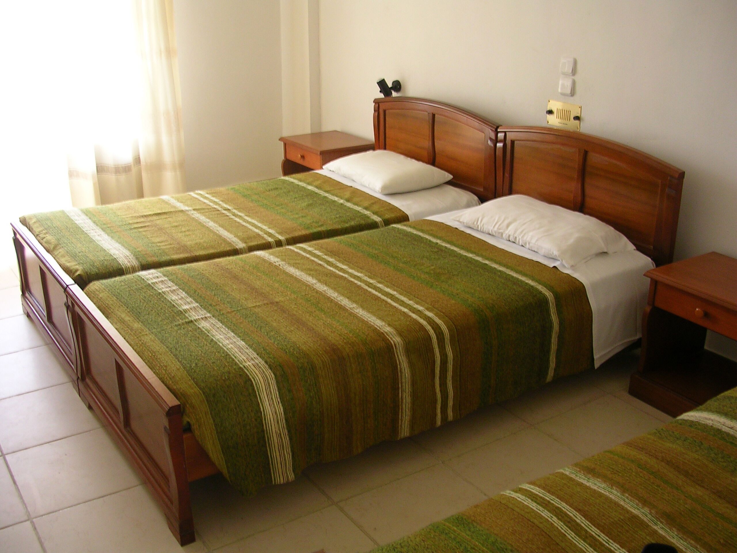 A double bed with a wooden headboard, two bedside tables, and a striped bedspread.