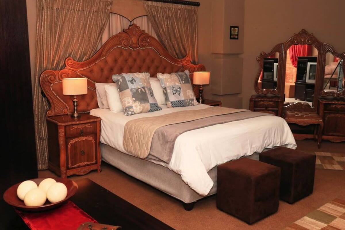 Une chambre avec un grand lit, deux tables de chevet, un miroir et un tapis rouge.