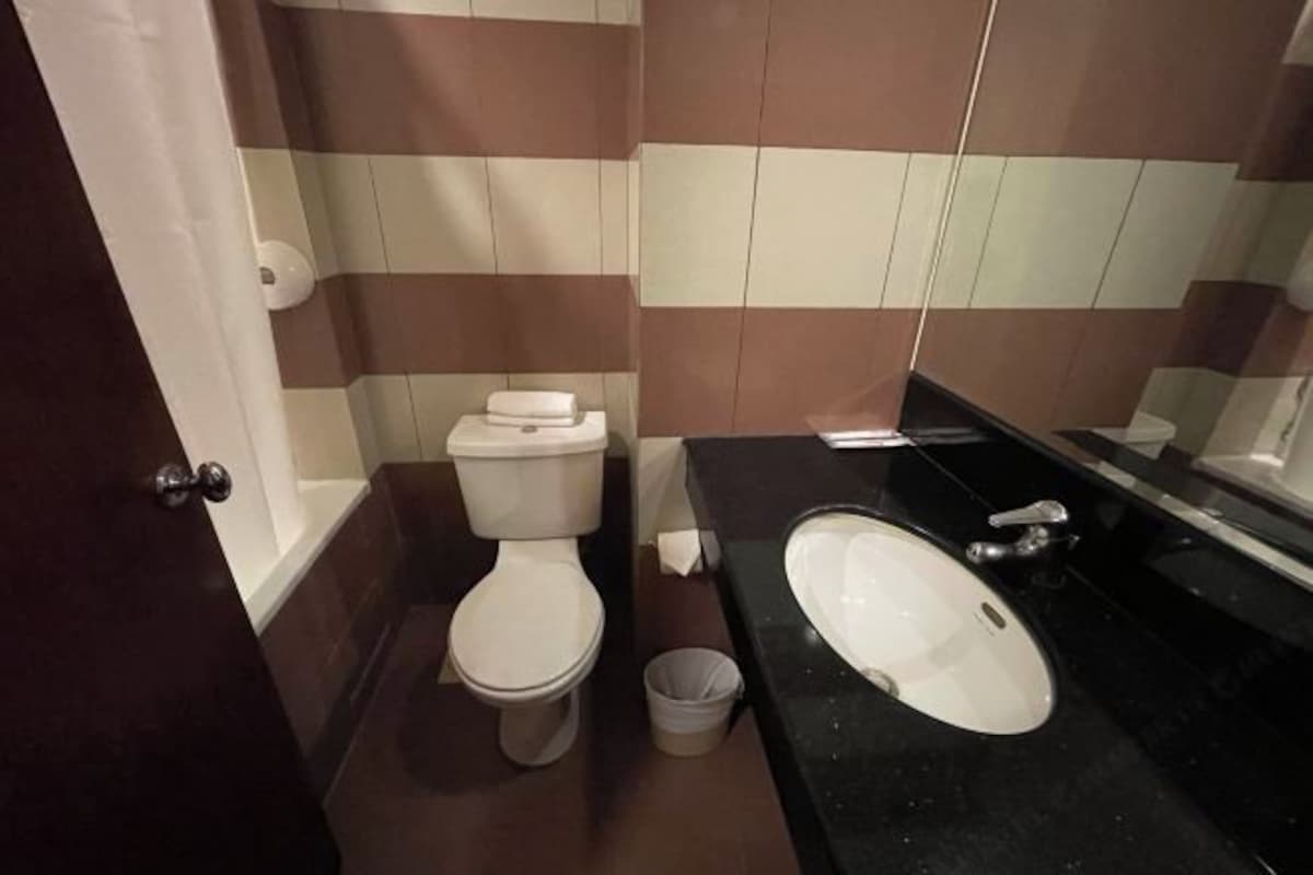 A bathroom with a toilet, sink, and a trash bin.