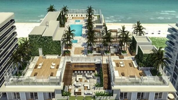 Un espace piscine aménagé sur le toit, avec des chaises longues et une piscine, entouré de palmiers et offrant une vue sur la plage.