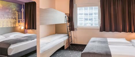 A hotel room with two beds, a bunk bed, a window with curtains, a wall mural, and a patterned carpet.