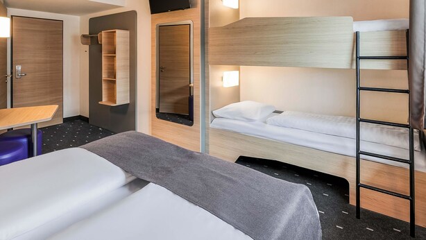A hotel room with a bunk bed, a desk, a chair, a TV, and a mirror. - B&B Hotel Stuttgart-Vaihingen (Stuttgart)