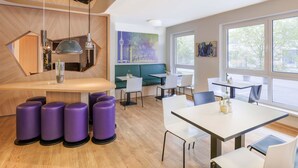 A modern dining area with wooden flooring, purple stools, and a green booth. - B&B Hotel Stuttgart-Vaihingen (Stuttgart)