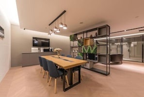 Una cocina moderna con zona de comedor, televisor de pantalla plana y estantería con plantas.