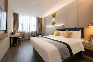 Una habitación de hotel con una cama grande, un escritorio, una silla y una ventana con cortinas.