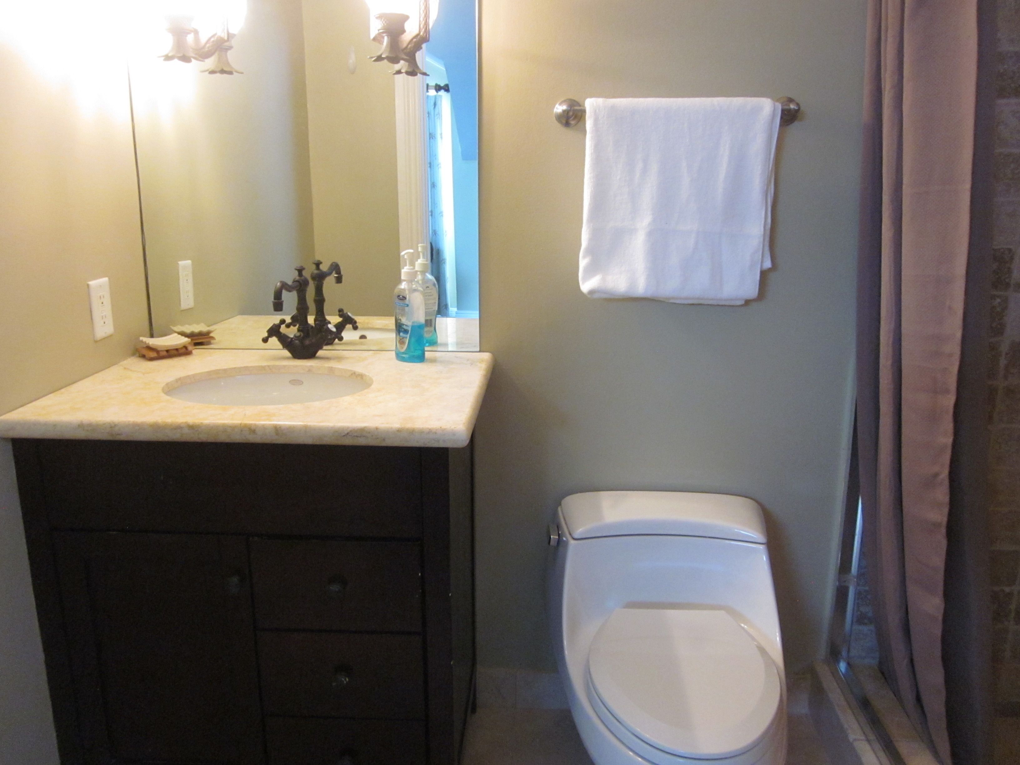 A bathroom with a sink, mirror, toilet, and towel rack.