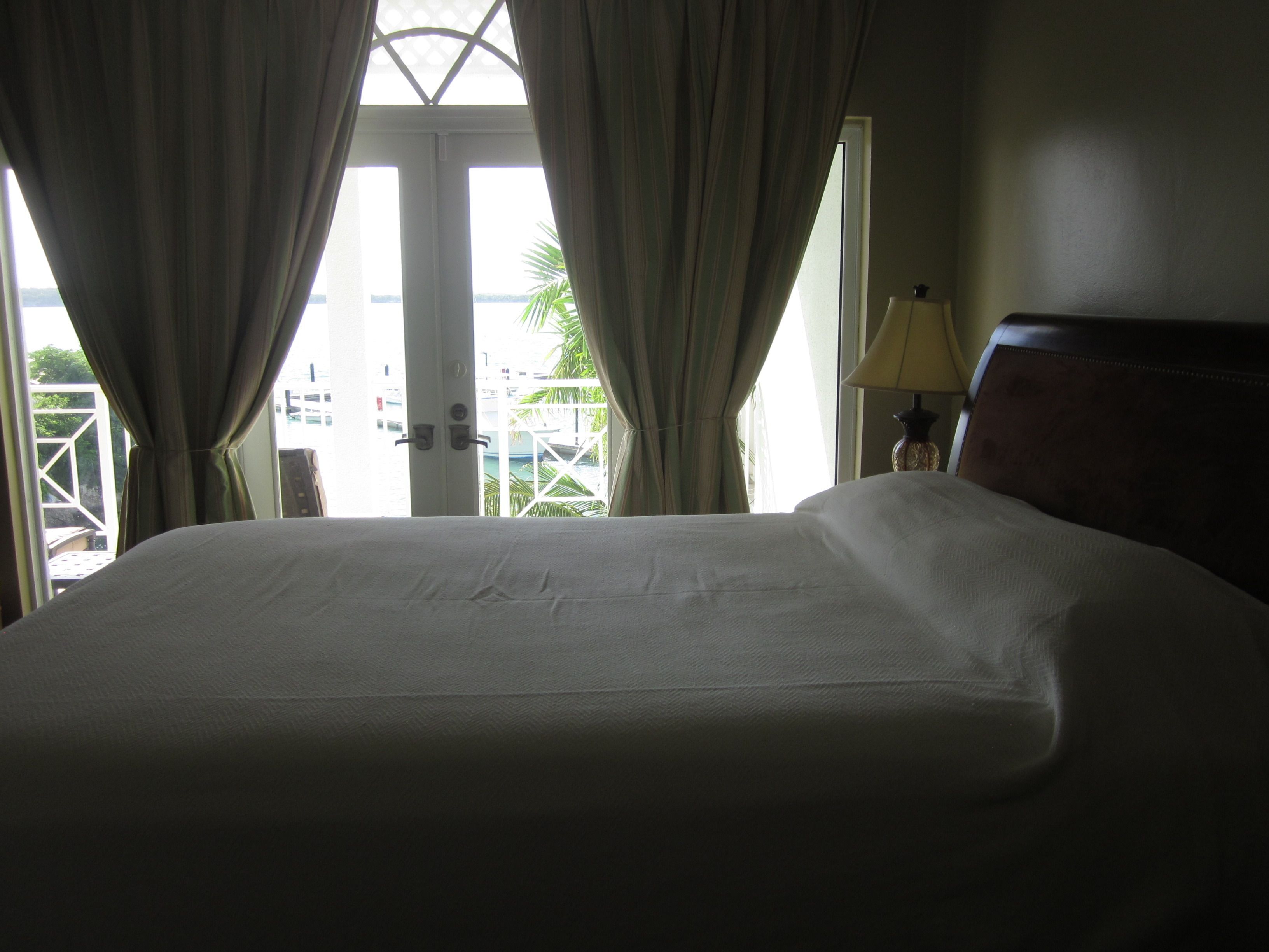 Une chambre d’hôtel avec un lit, des rideaux, une lampe et une vue sur l’extérieur.