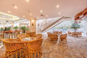 Un vestíbulo de hotel con muebles de mimbre, piso estampado y una escalera.