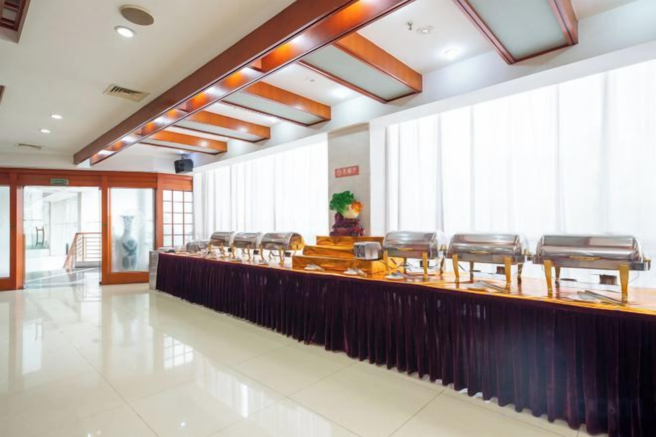 Montaje tipo bufé con varias estaciones de servicio, una mesa larga y vista despejada a la sala contigua.