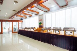 Montaje tipo bufé con varias estaciones de servicio, una mesa larga y vista despejada a la sala contigua.