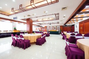 Un salón de banquetes con mesas y sillas redondas, una zona de buffet y un mostrador de recepción.