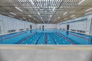 Una piscina interior con varias pistas, suelo de baldosas y techo con diseño de cuadrícula.