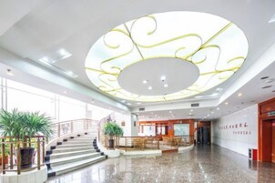 Un lobby amplio con una escalera central, una recepción y un gran diseño de techo circular.