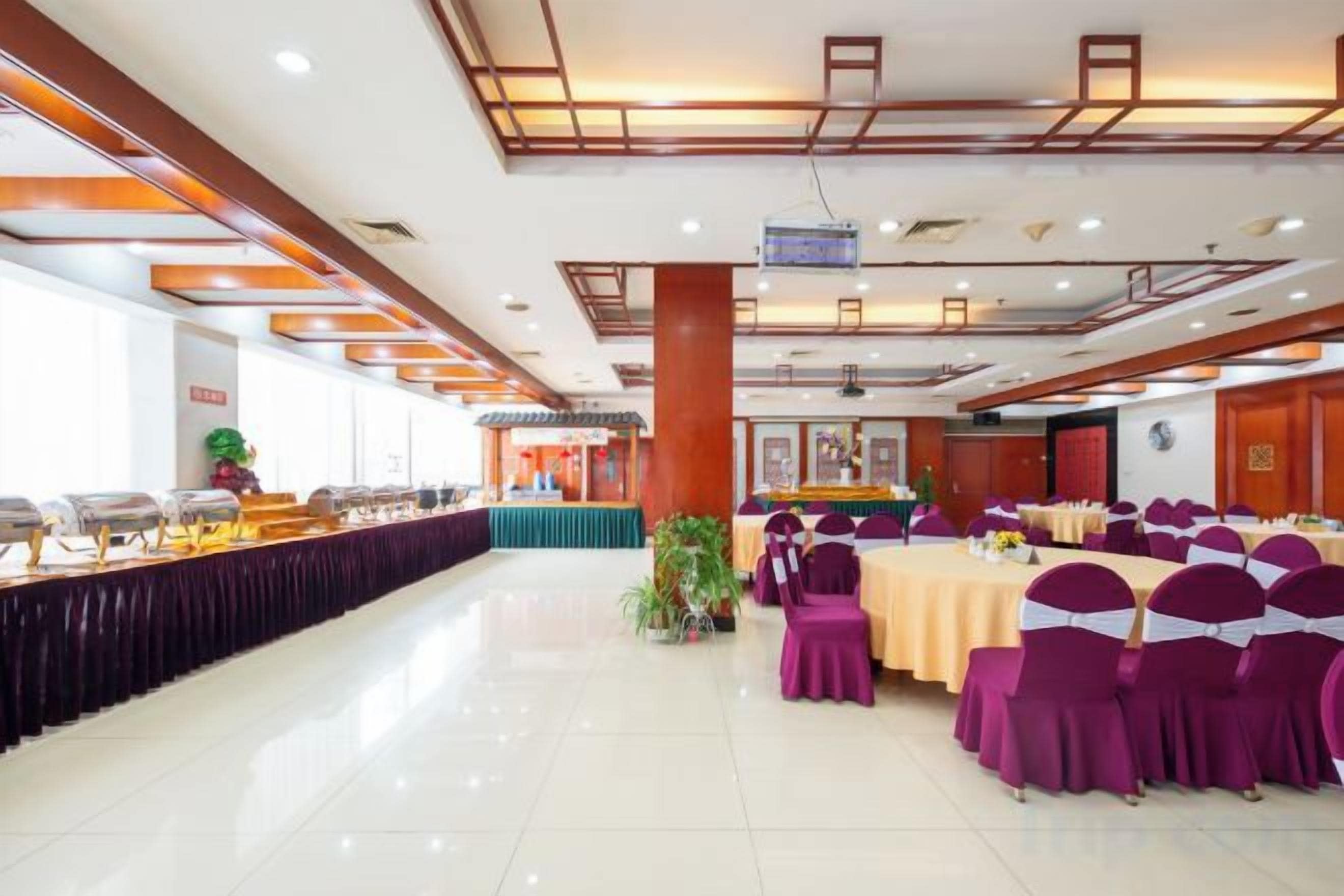 A banquet hall with a long table, chairs, and a stage area.