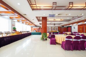 A banquet hall with a long table, chairs, and a stage area.