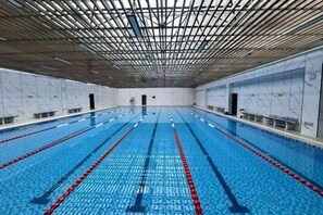 En inomhuspool med flera banor, ett tak med ett rutmönster och väggar med fönster.