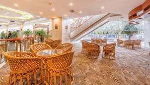 Eine Hotelhalle mit Korbmöbeln, einem gemusterten Boden und einer Treppe.