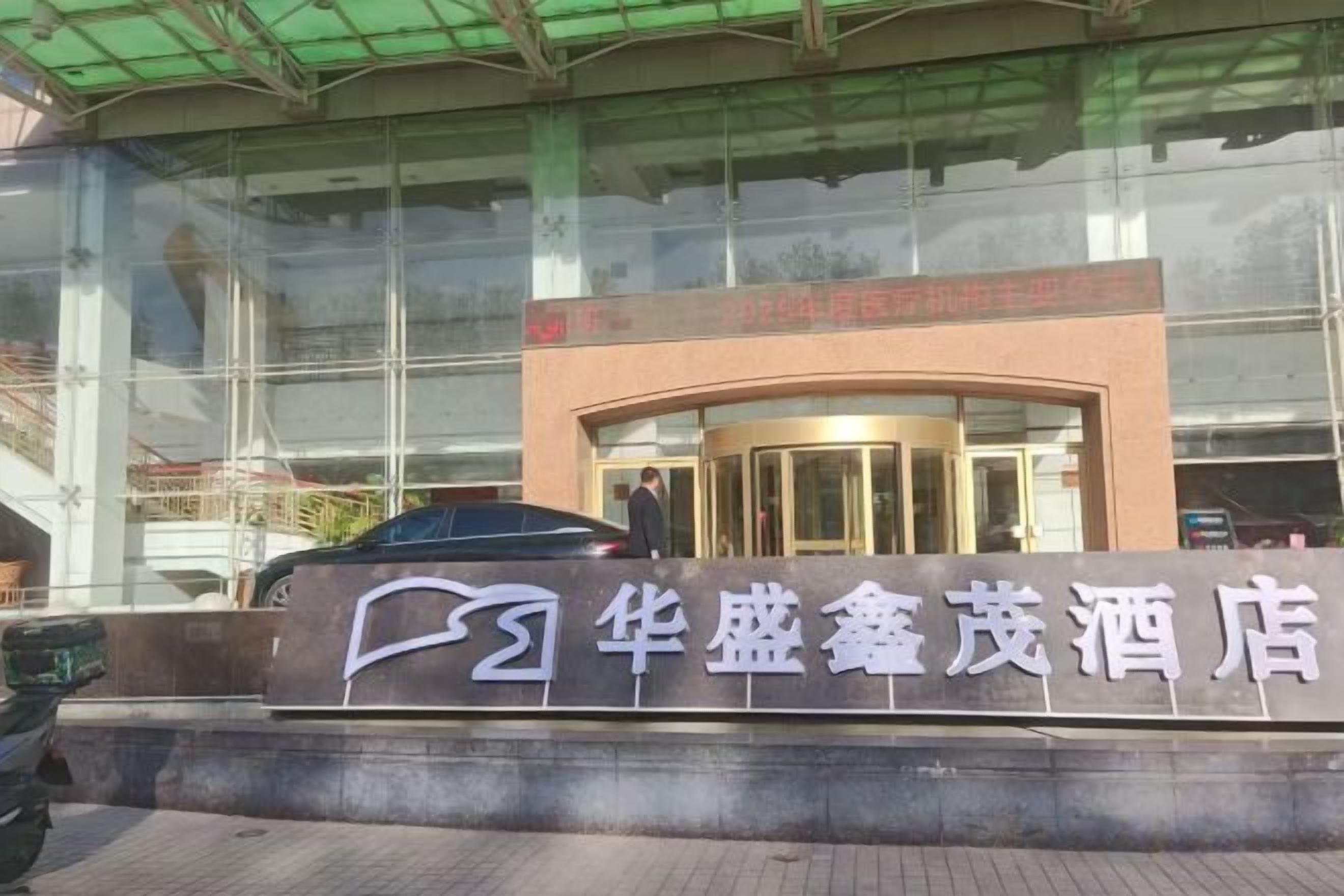 A hotel entrance with a sign, a glass door, and a person standing in front.
