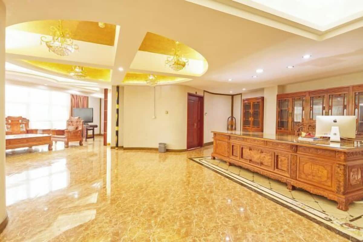 A spacious living area with a marble floor, wooden furniture, and a large wooden cabinet.