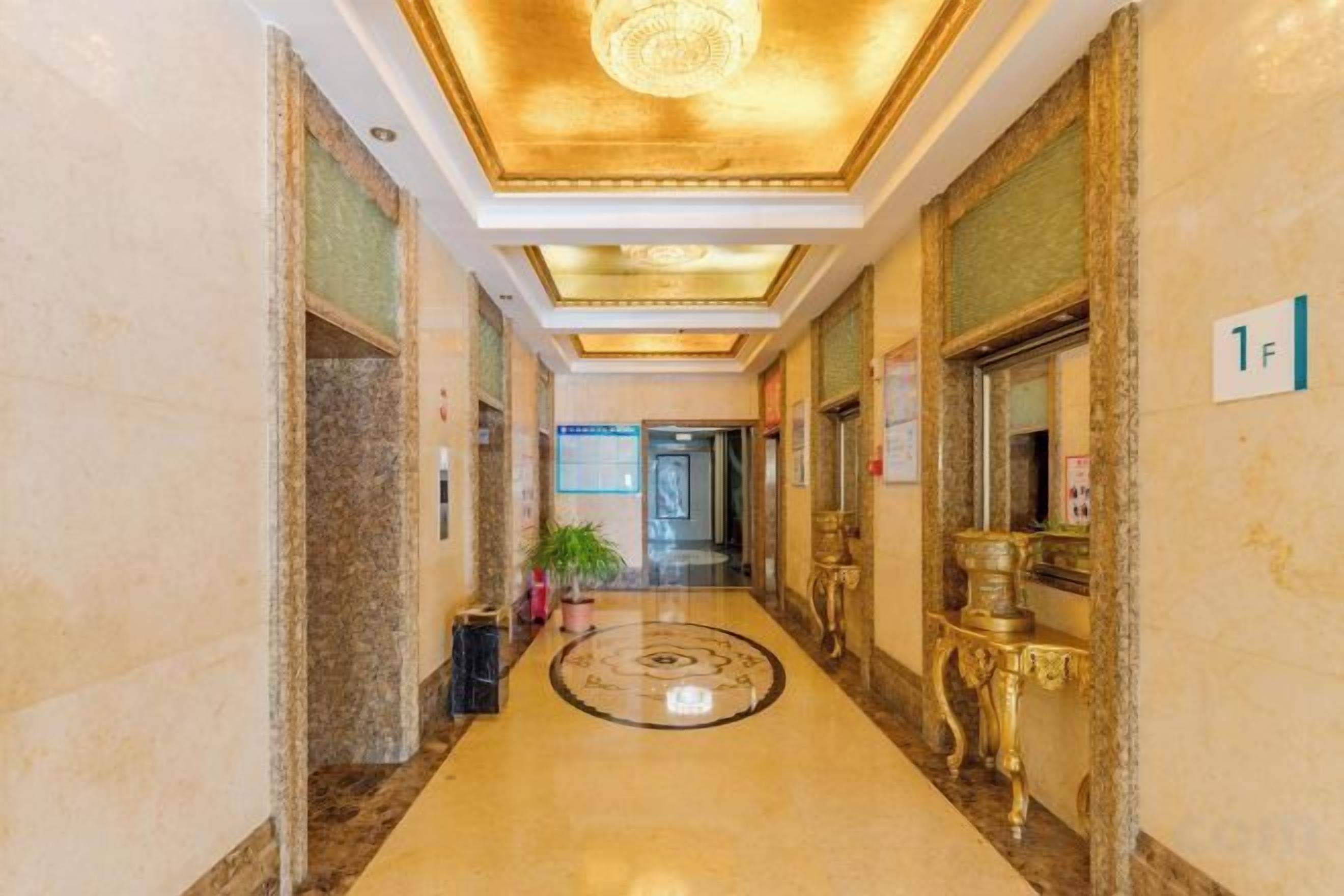 A hotel corridor with marble flooring, a chandelier, and a sign indicating room 1F.