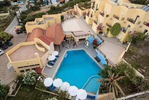 A residential building with a swimming pool, outdoor seating, and a garden area.