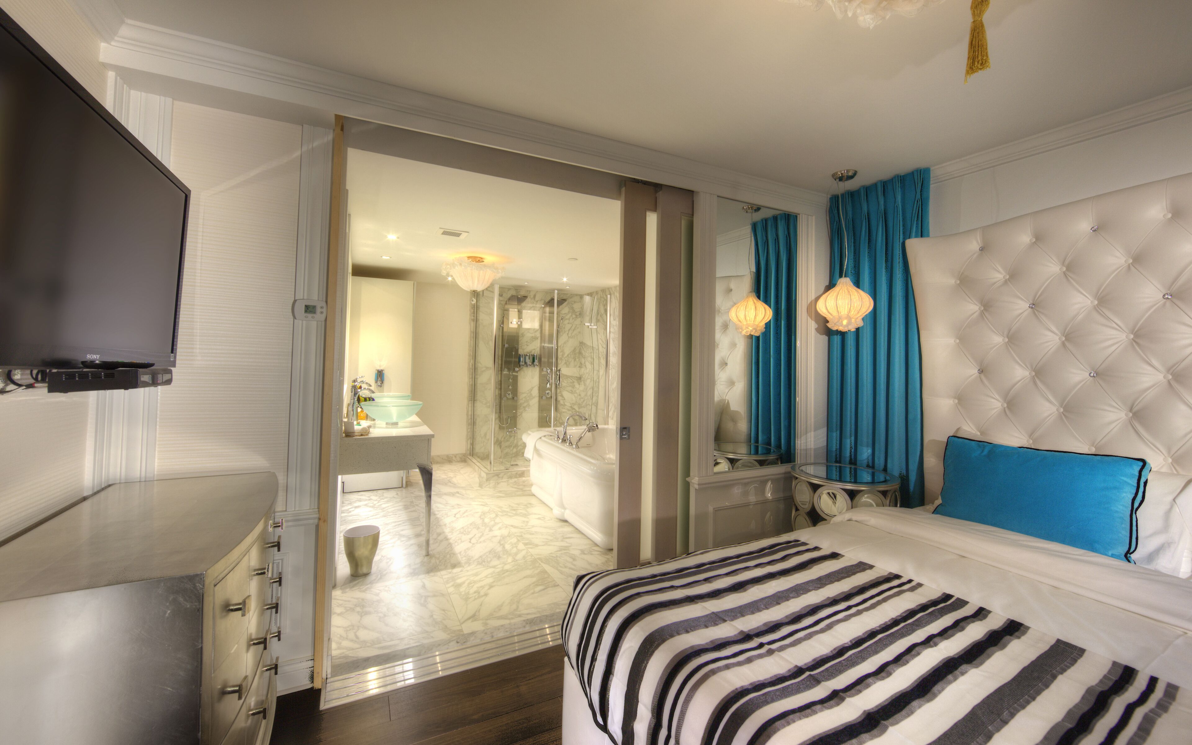 A hotel room with a bed, a TV, a bathroom with a bathtub, and a shower.