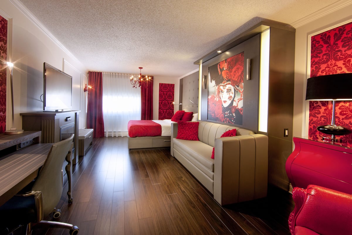 Una habitación de hotel moderna con una cama grande, una zona de estar y un televisor.