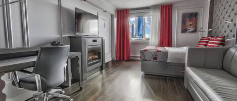 A modern hotel room with a desk, chair, sofa, and a bed.