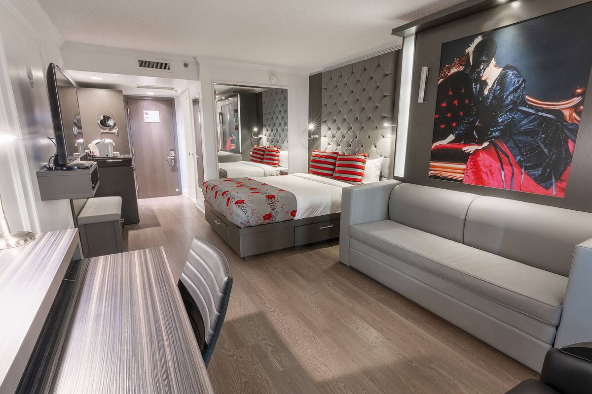 Una habitación de hotel moderna con una cama, un sofá, un escritorio y un cuadro grande en la pared.