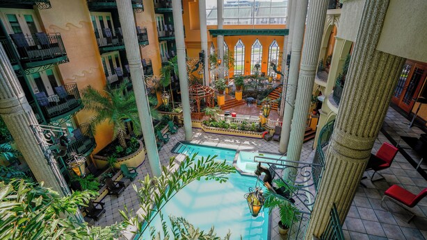An indoor atrium with a central pool, multiple balconies, and lush greenery.