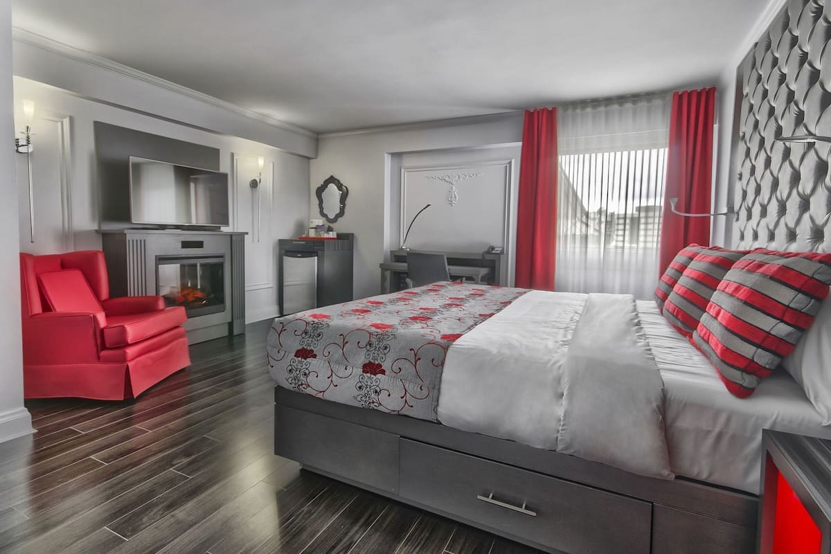 Un dormitorio moderno con cama, escritorio, silla y chimenea.