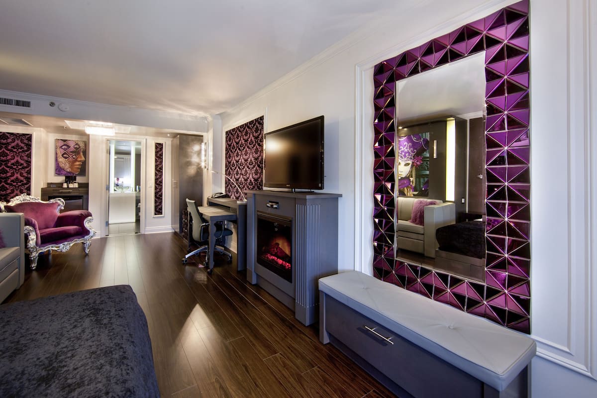Una sala de estar moderna con chimenea, televisor y un espejo grande con diseño geométrico.