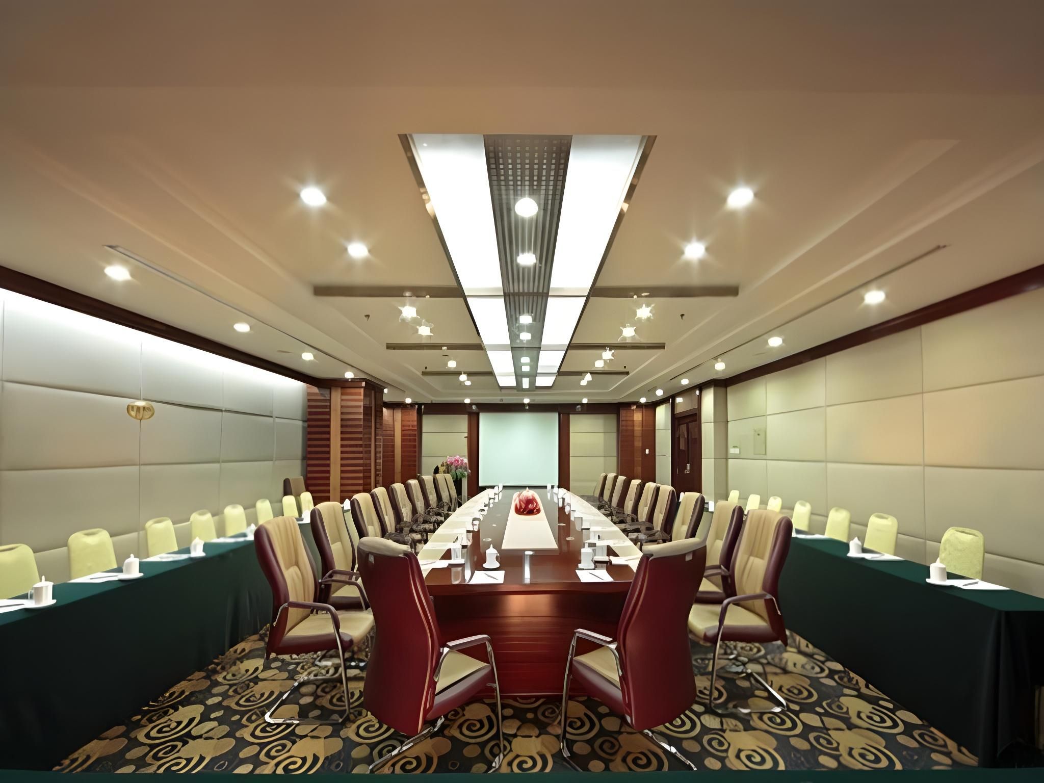 A conference room with a long table, chairs, and a projector screen.