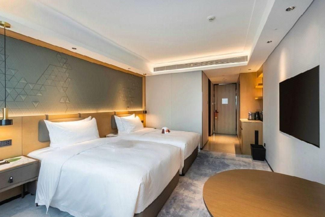 Habitación de hotel con dos camas, televisión de pantalla plana, escritorio y diseño moderno.