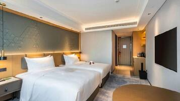 Habitación de hotel con dos camas, televisión de pantalla plana, escritorio y diseño moderno.