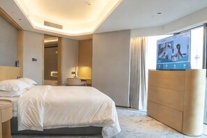 A modern hotel room with a large bed, a TV on a stand, a bedside table, and a view of the outside.
